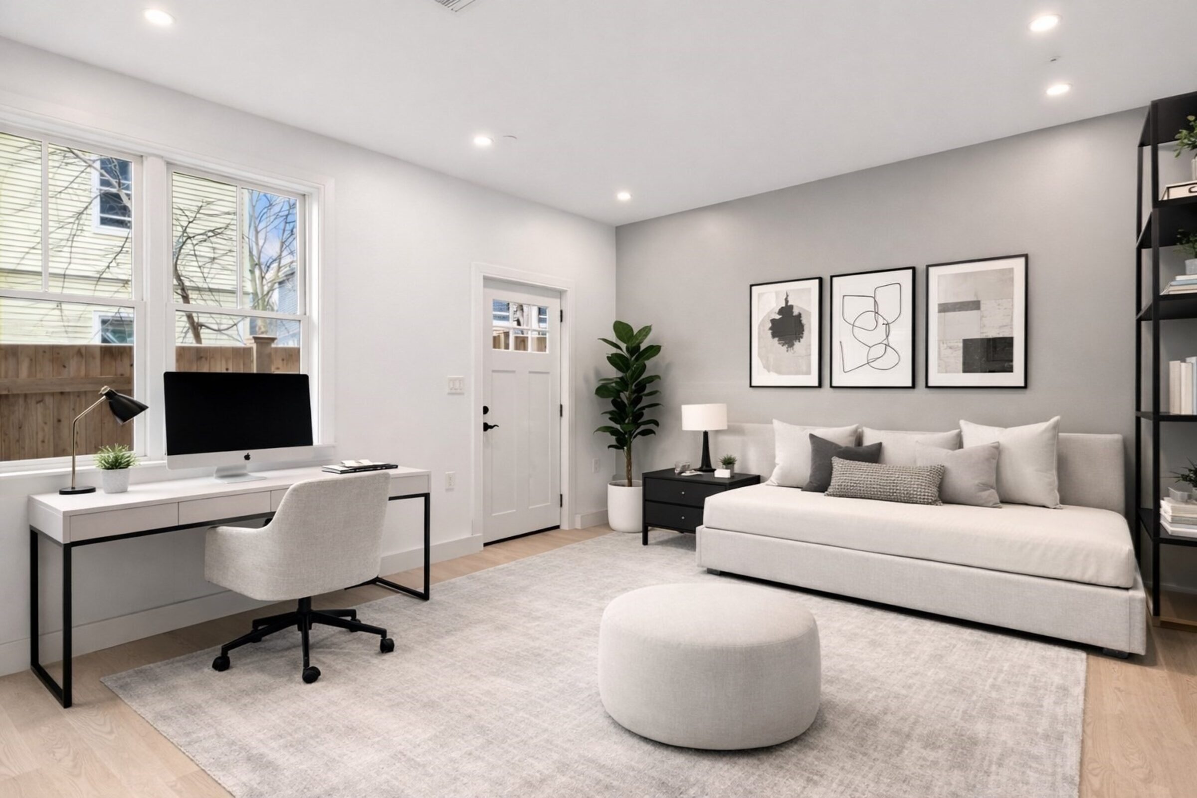 Flexible living space with a desk, daybed, and built-in shelving, suited for a home office.