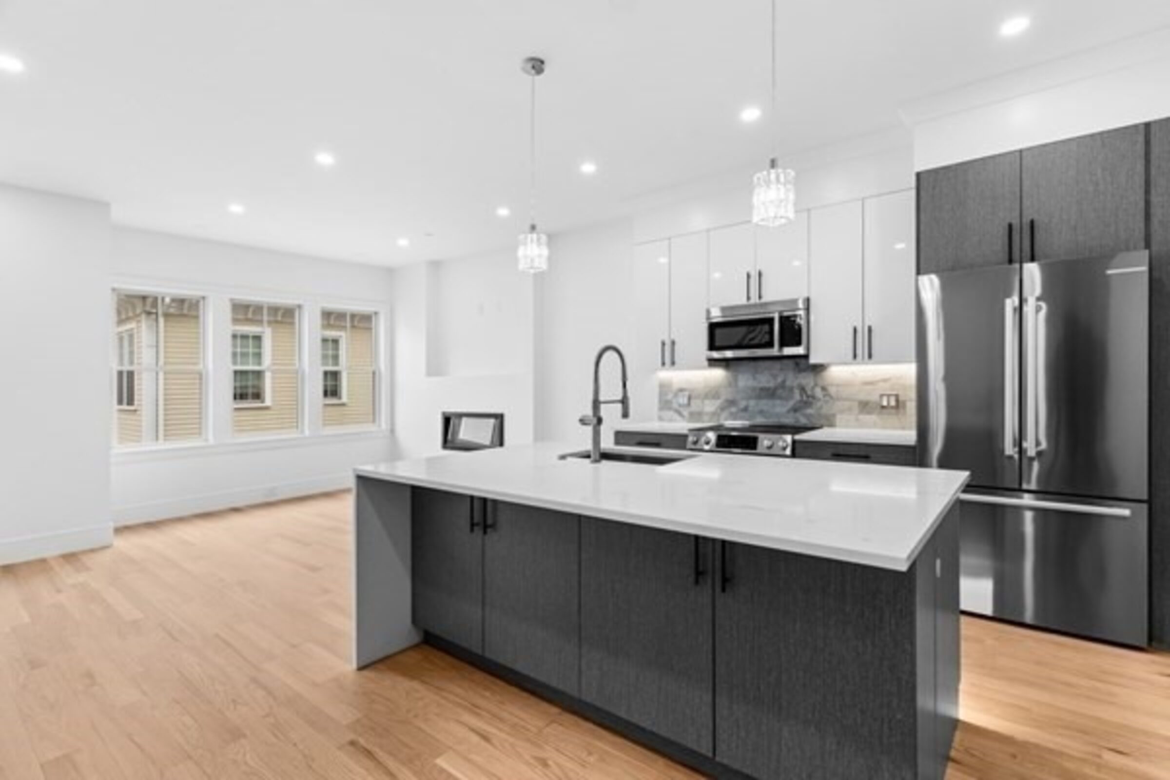 Kitchen with dark cabinetry, quartz island, and stainless steel appliances.