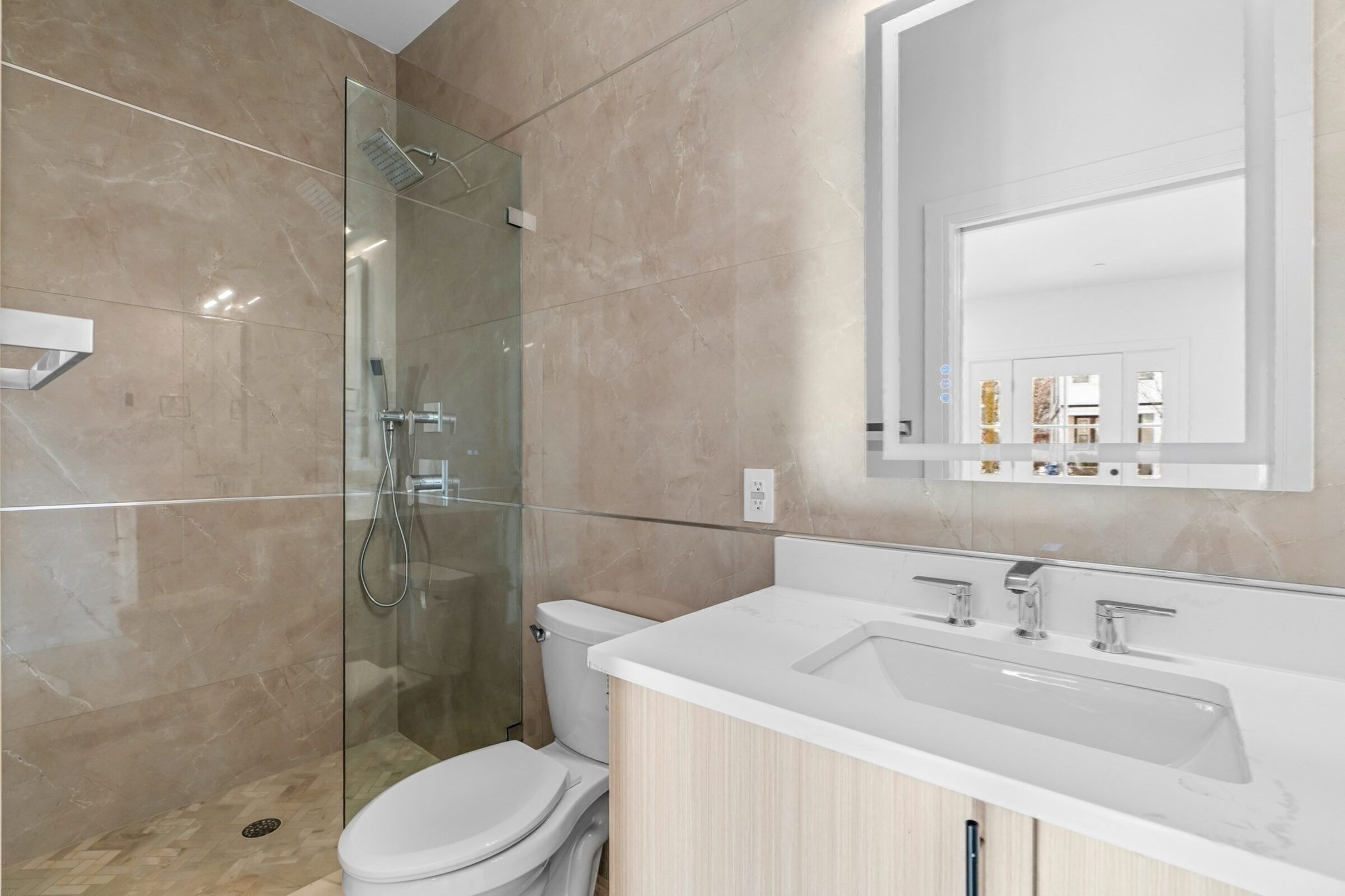 Bathroom with a glass-enclosed shower and marble-tiled walls.